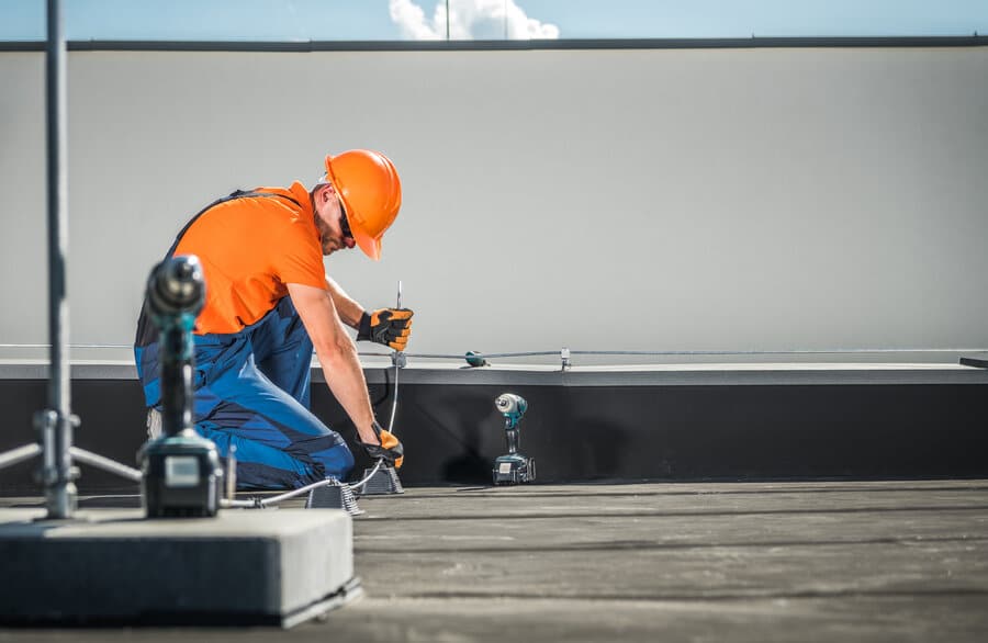 lightning-protection-system Laswell Electric electrician installing a lightning protection system on the roof of an office building, ensuring safety and compliance with industry standards for electrical systems.