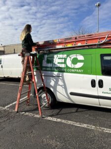 Marianne taking a ladder from a Laswell Electric van, showcasing the team’s readiness for commercial and residential electrical work.